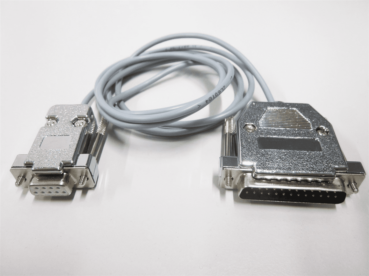 Aufgerolltes, graues Schnittstellenkabel auf weißem Hintergrund. An beiden Enden ist ein HDMI-Stecker, eins weiblich und eins männlich.