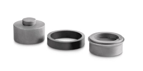 Drei Kleinteile auf weißem Hintergrund. Die Teile dienen als Zubehör für Kraftmessdosen. Das sind zwei Teile und ein Ring aus Gummi.